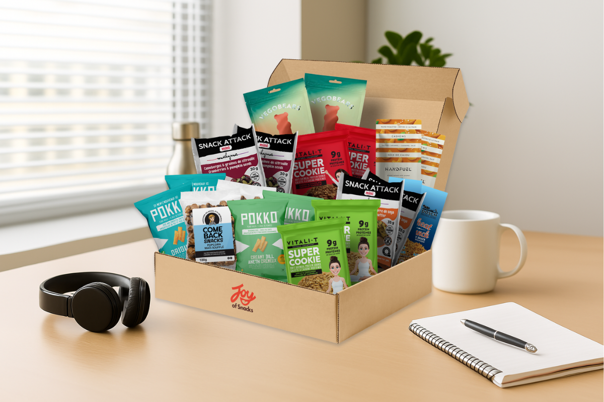 Joy of Snacks Shared Joy box on a desk in a modern office with a mug, headphones and paper and pen